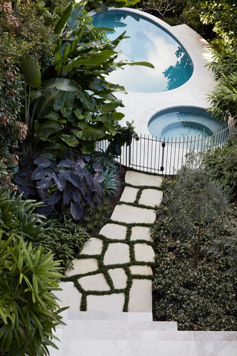 Crazy paving, softened by the moss between each paver, leads to the elliptical pool terrace, which has two circular pool of different sizes at each end