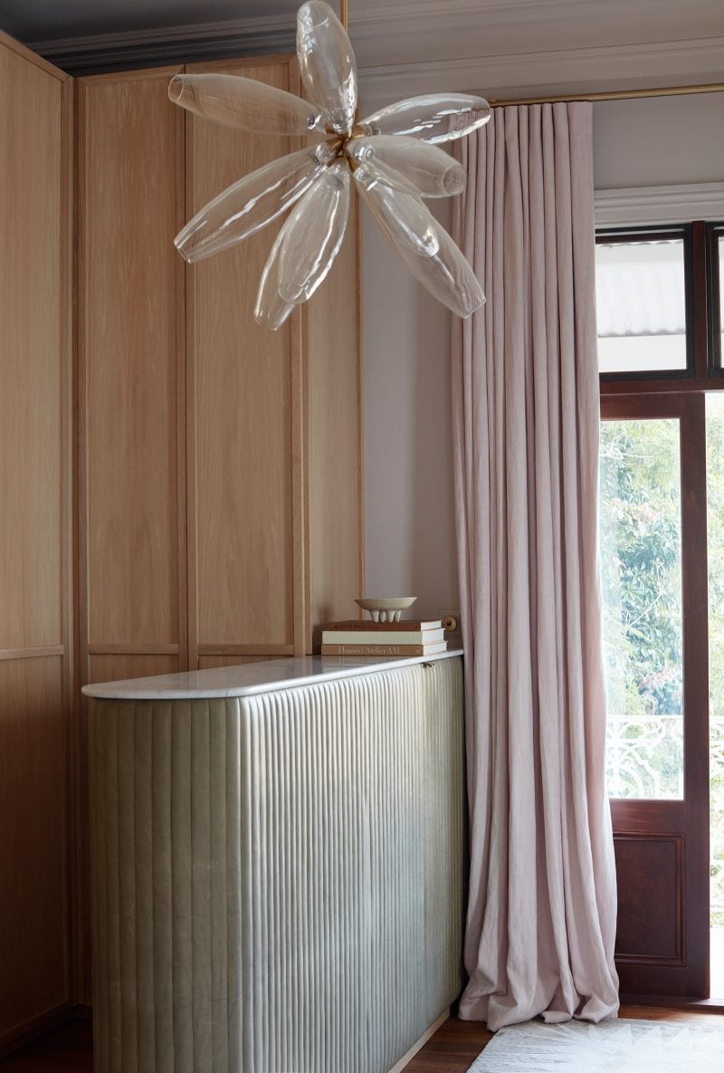 A fluted cabinet wrapped in brown Verona leather, with a crystalline pendant light hanging above, distinguishes the wardrobe space in the master bedroom