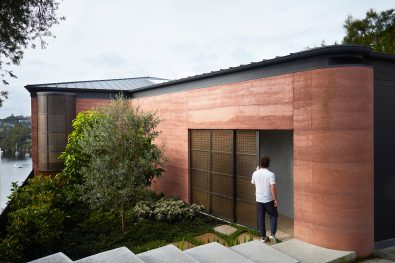 Luigi Rosselli's Earth-ship has a rammed earth façade and grey Corten roof. Project architect Nicola Ghirardi slides the brass mesh entrance door open