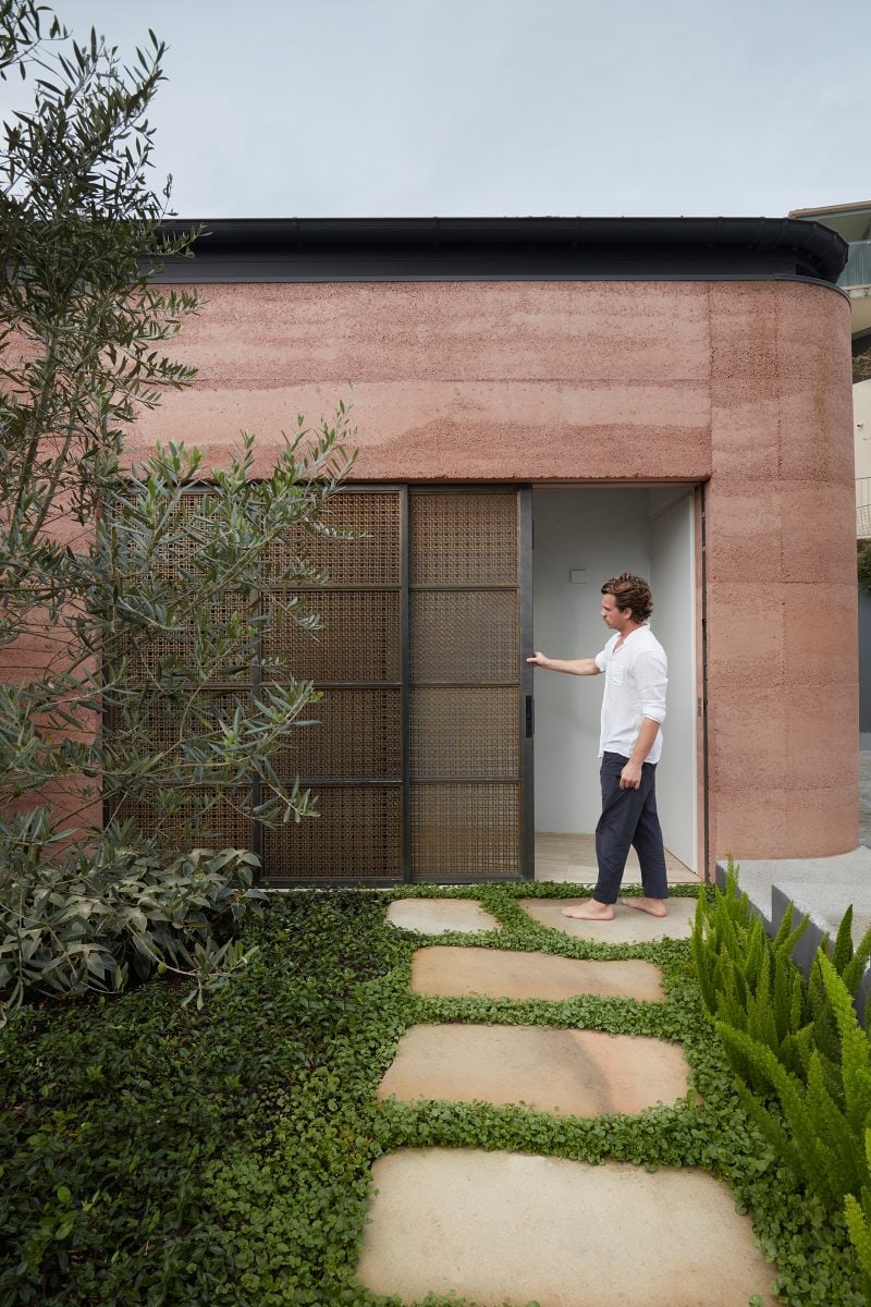 Amidst lush landscape by DBS, Project architect Nicola Ghirardi demonstrates the brass mesh entrance door sliding mechanism