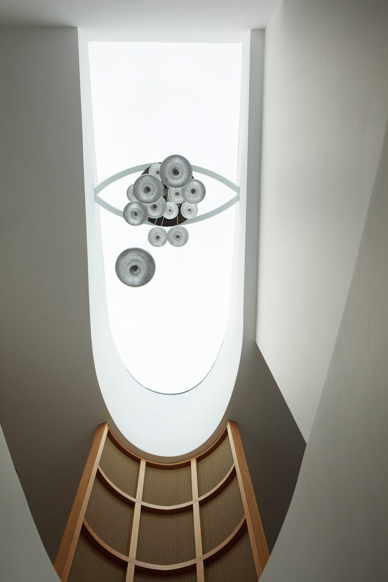 Looking up at the skylight above the stairs, the many glass baubles and the white frame of the pendant looks like an eye with multiple irises