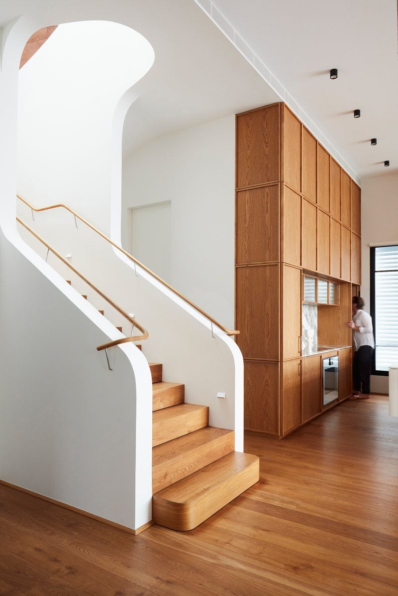 The staircase curves, in signature Luigi Rosselli style, into the kitchen. Sunlight from the skylight two stories above illuminates the stairwell