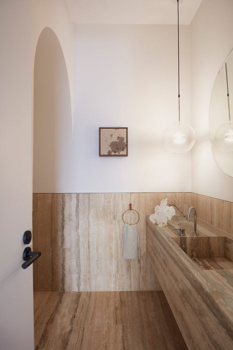 Luigi Rosselli Earth-ship, stone tile vanity and flooring of the ensuite, with a thick arch entrance