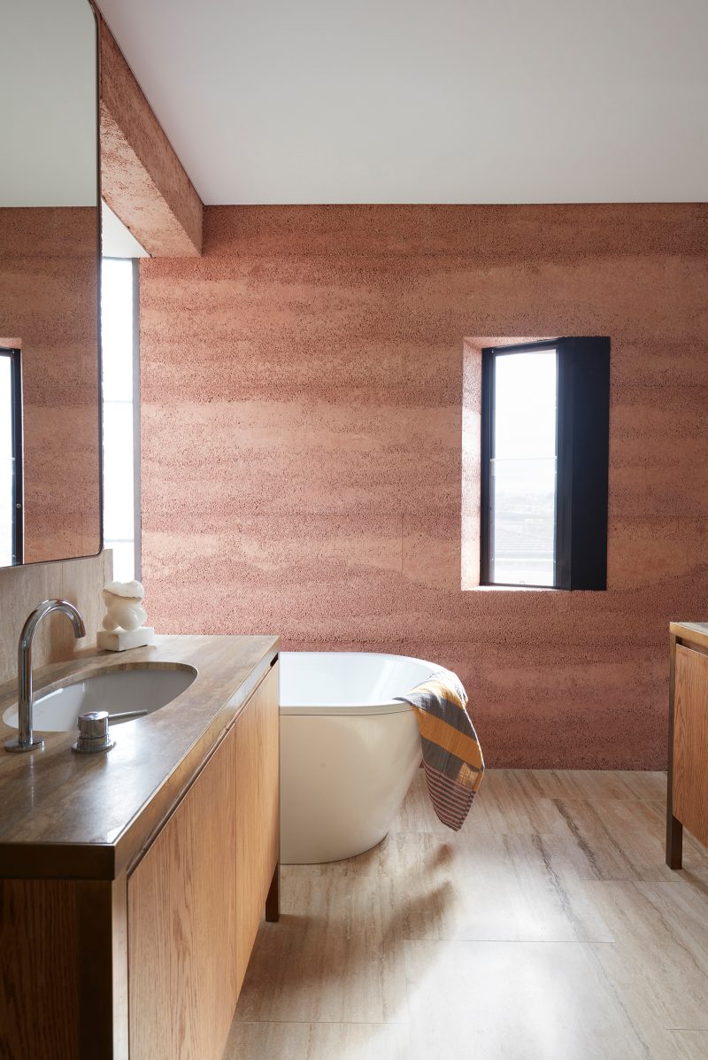 Luigi Rosselli, Earth-ship's master ensuite sports timber flooring and rammed earth walls, with black framed windows recessed into the thick walls