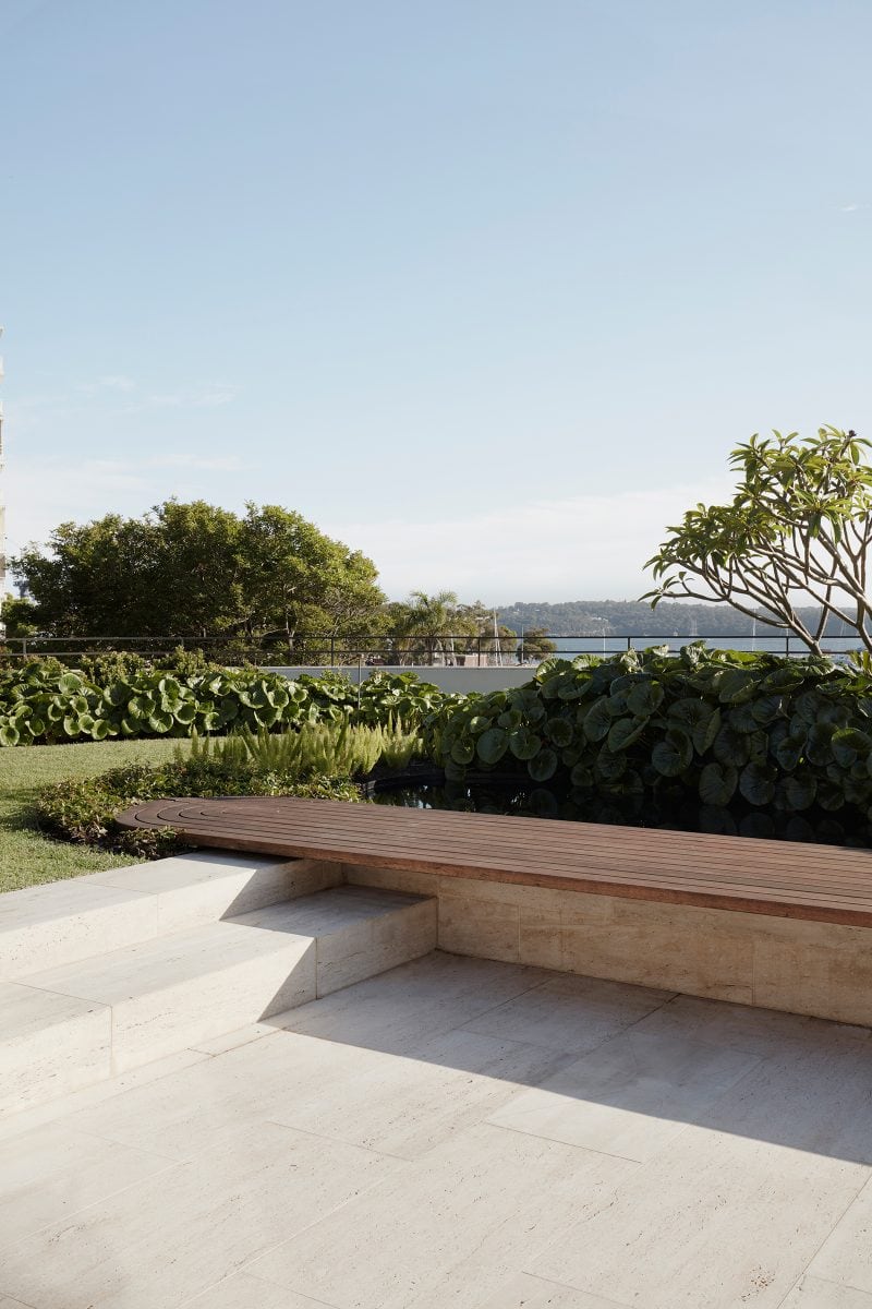 Luigi Rosselli curved timber seat set in a manicured green lawn overlooking the Sydney Harbor, travertine steps