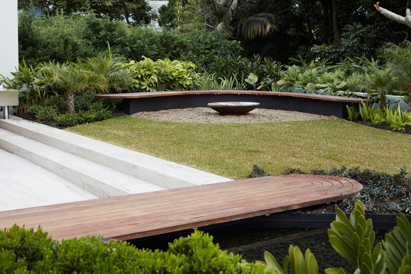 Timber curved benches set in a manicured garden, with travertine steps