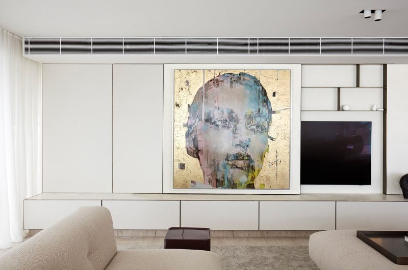 Luigi Rosselli, the statement gold wall art of a woman's face sliding to reveal the recessed TV unit behind the panel