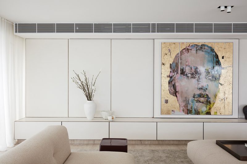 Luigi Rosselli, the statement gold wall art of a woman's face sliding to hide the recessed TV unit behind the panel