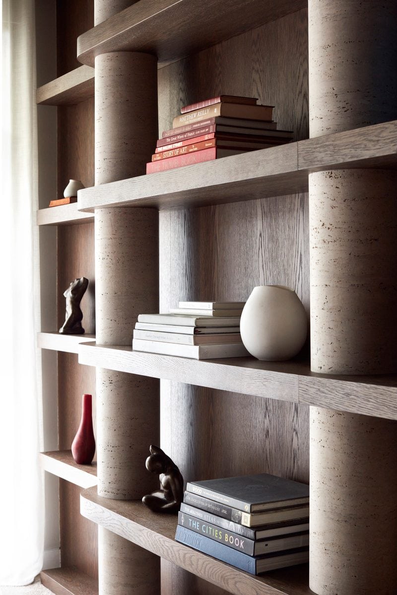 Luigi Rosselli signature rammed earth pillar forms part of the timber display shelves built into the wall, vases and books lines the shelves