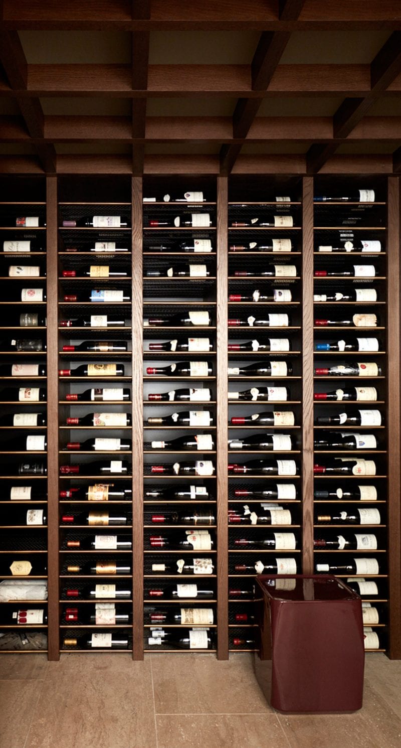 Timber shelving lines the walls from top to bottom, each compartment holding a wine bottle on display