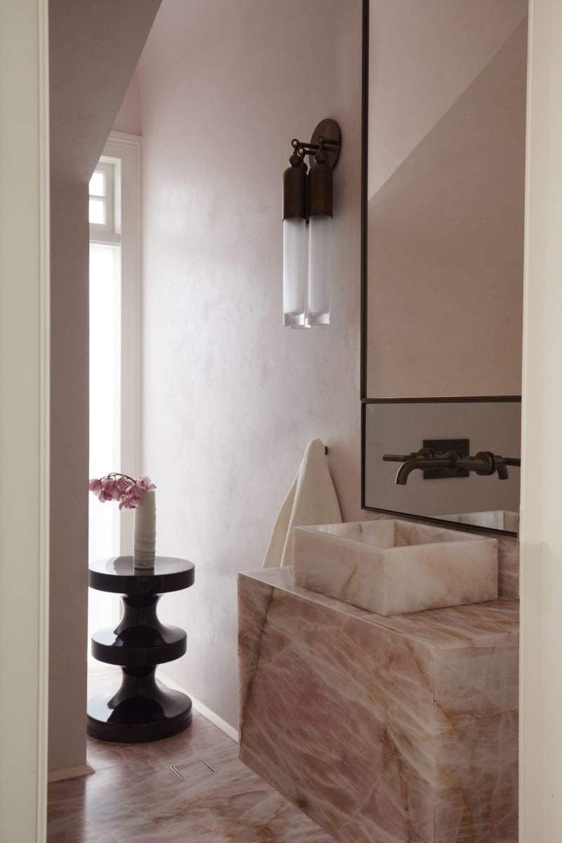 A bathroom vanity, sink and flooring of pink marble with streaks of white