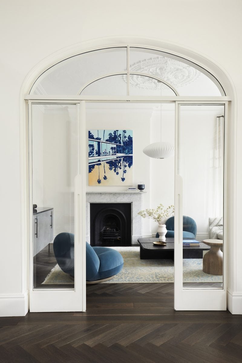 The glass door from the living room to the rumpus is framed in white timber, with two fixed glass panel on either side and a glass arch over the door