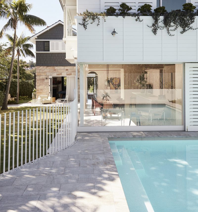 full length glass window visually connects the dining room to the swimming pool, minimalistic white pool fence, white sliding shutters