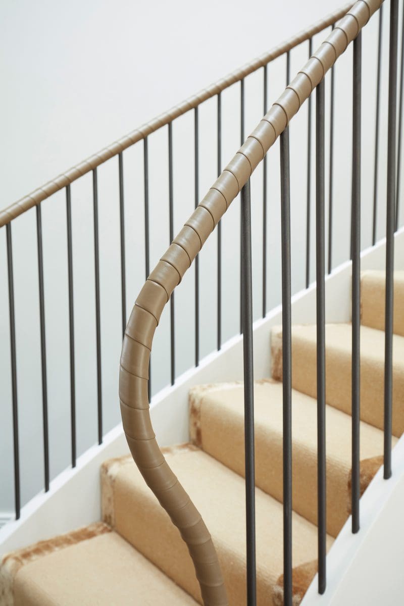 brown leather-wrapped curved handrail and cream silk carpetsteps
